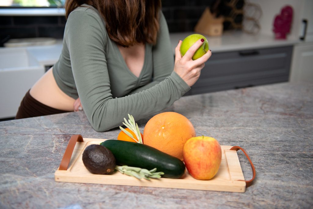 Women holding apple at counter.