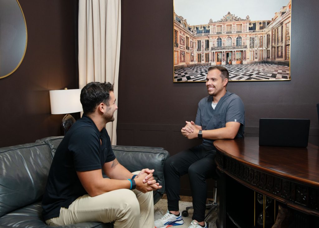 Dr. Kasey speaking with patient at his desk.