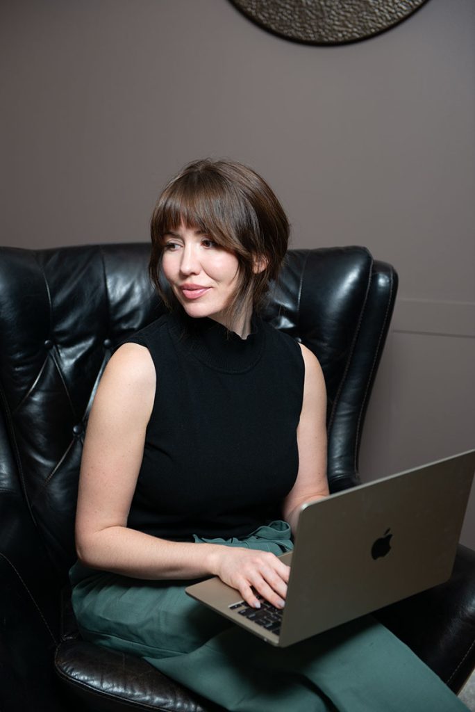 Dr Stephanie looking away from computer while consulting with client online.